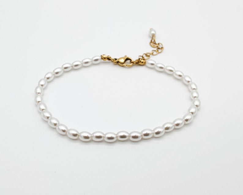 May include: A delicate white pearl bracelet with a gold clasp.