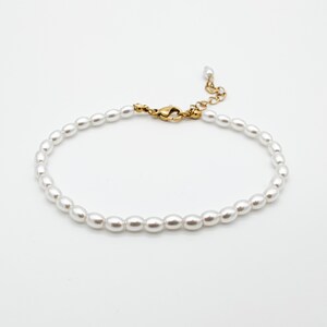 May include: A dainty pearl bracelet with a gold clasp. The bracelet is made of small, white pearls and is ideal for adding a touch of elegance to any outfit.