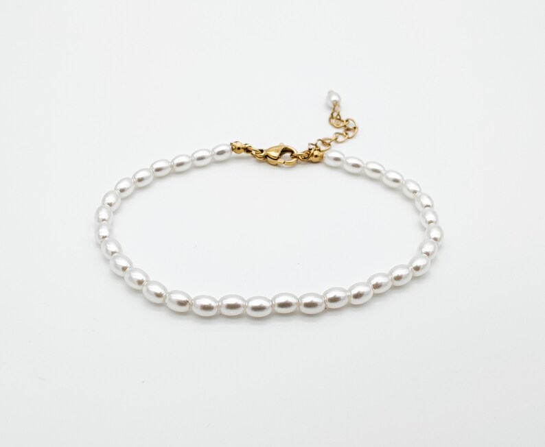 May include: A dainty pearl bracelet with a gold clasp. The bracelet is made of small, white pearls and is ideal for adding a touch of elegance to any outfit.