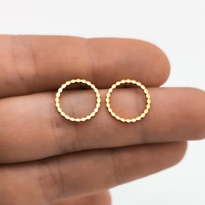 Pode incluir: Um par de brincos de pressão circulares dourados com uma borda de contas.