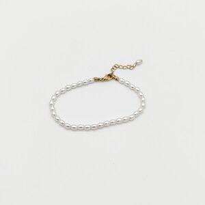 May include: A delicate white pearl bracelet with a gold clasp.