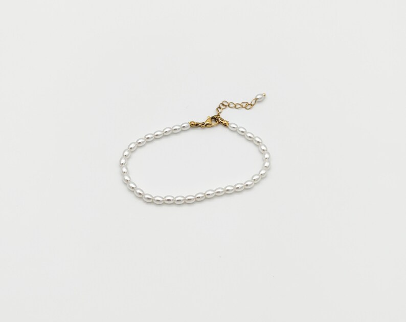May include: A delicate white pearl bracelet with a gold clasp.