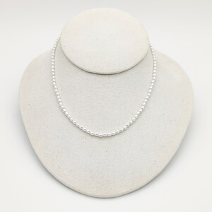 May include: A simple silver necklace with small round beads.