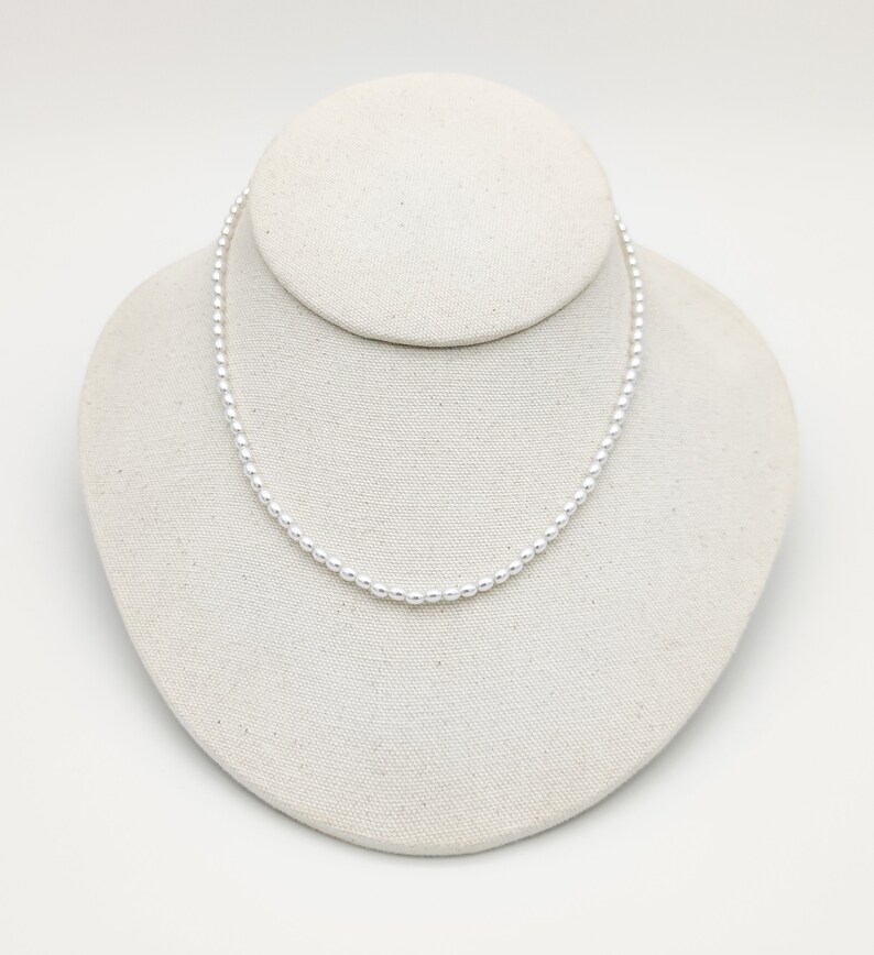 May include: A simple silver necklace with small round beads.