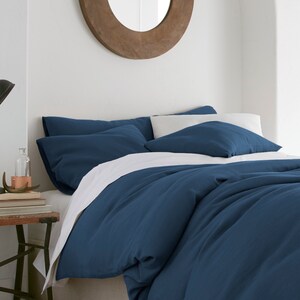 Puede incluir: Una funda n&oacute;rdica azul con fundas de almohada blancas. La funda n&oacute;rdica est&aacute; hecha de una tela suave y c&oacute;moda y tiene un aspecto relajado y casual.