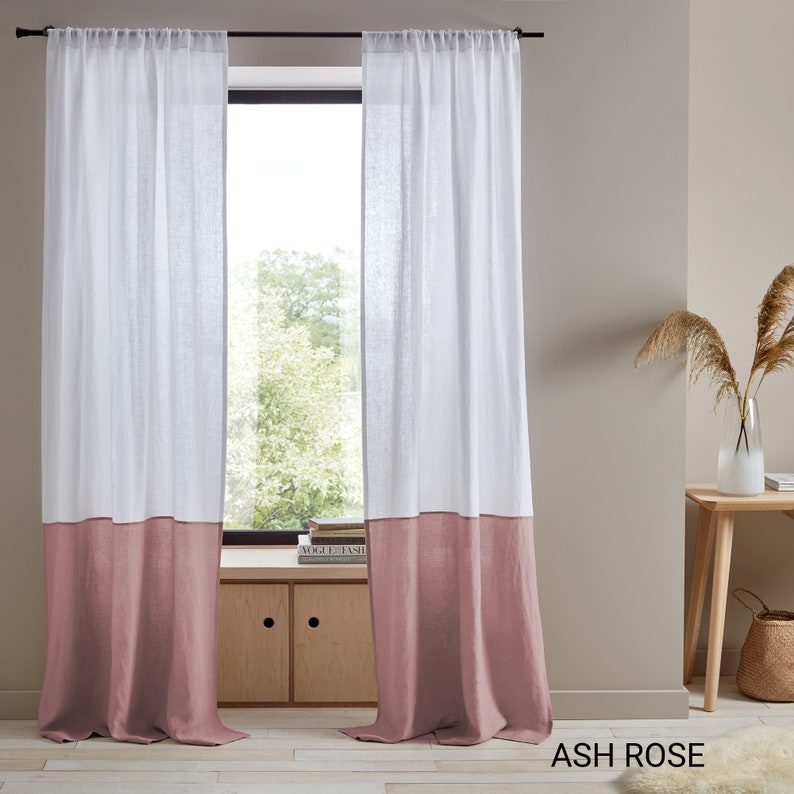 May include: Two white linen curtains with a bottom panel of a dusty rose color. The curtains are hung on a black curtain rod. The text "ASH ROSE" is visible in the bottom right corner of the image.