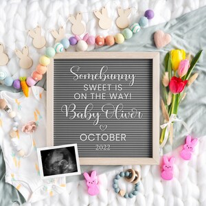 Puede incluir: Un tablero de letras gris con el texto "Somebunny sweet is on the way! Baby Oliver October 2022". El tablero est&aacute; rodeado de bolas de fieltro de colores pastel, recortes de conejitos de madera y un ramo de tulipanes amarillos y rojos.
