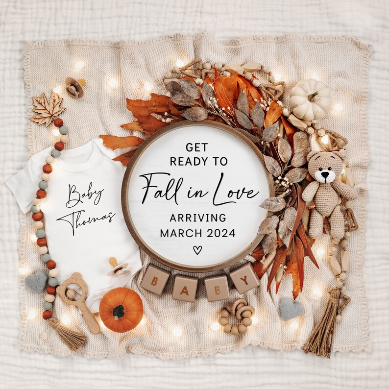 May include: A fall-themed baby announcement with a white onesie that says "Baby Thomas", a wooden sign that says "Get Ready to Fall in Love Arriving March 2024", a small pumpkin, and wooden blocks that spell out "BABY".