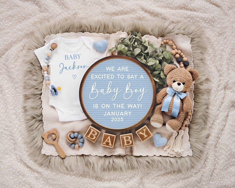 May include: A blue and white letter board with the text "We are excited to say a Baby Boy is on the way! January 2025".  The letter board is surrounded by a white onesie with the text "Baby Jackson", a blue and white teddy bear, and wooden blocks that spell out "Baby".