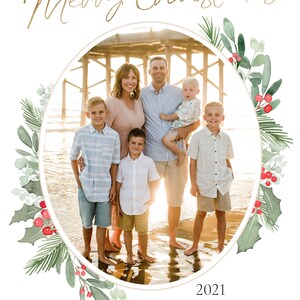 Puede incluir: Una tarjeta de Navidad con una familia de seis personas de pie en una playa frente a un muelle. La familia sonr&iacute;e y mira a la c&aacute;mara. La tarjeta est&aacute; decorada con una corona de acuarela de acebo y vegetaci&oacute;n. El texto "Merry Christmas 2021 The Williams Family thomas + jessica jackson + ethan + cooper + dean" est&aacute; impreso en la tarjeta.