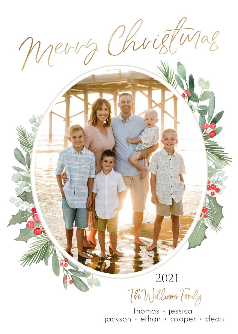 Puede incluir: Una tarjeta de Navidad con una familia de seis personas de pie en una playa frente a un muelle. La familia sonr&iacute;e y mira a la c&aacute;mara. La tarjeta est&aacute; decorada con una corona de acuarela de acebo y vegetaci&oacute;n. El texto "Merry Christmas 2021 The Williams Family thomas + jessica jackson + ethan + cooper + dean" est&aacute; impreso en la tarjeta.