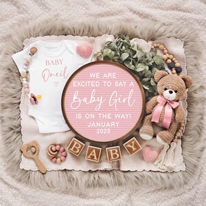 K&ouml;nnte beinhalten: Ein rosa-wei&szlig;es Buchstabenbrett mit dem Text "We are excited to say a Baby Girl is on the way! January 2025". Das Buchstabenbrett ist umgeben von einem wei&szlig;en Strampler mit dem Text "Baby Oneil", einem rosa-wei&szlig;en Teddyb&auml;r und Holzbl&ouml;cken, die "BABY" buchstabieren.