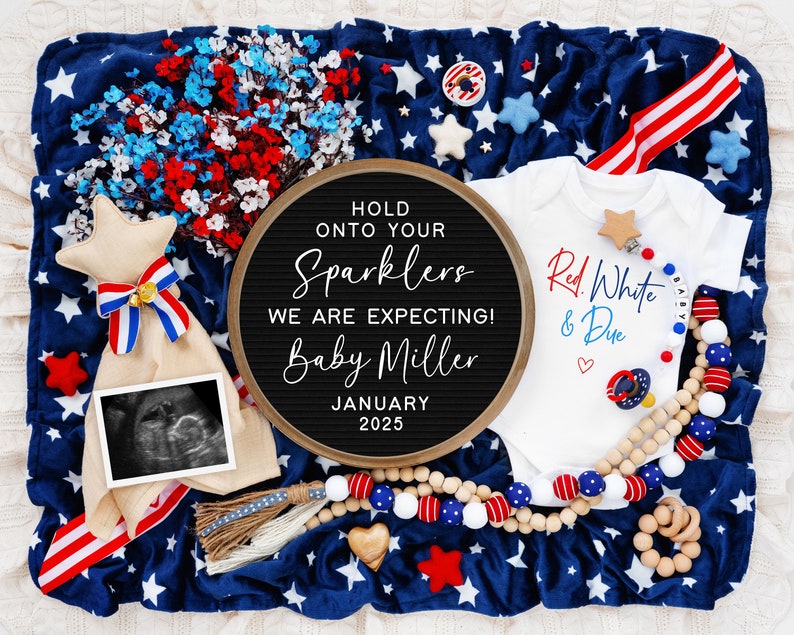 Op de afbeelding: Een rood, wit en blauwe baby romper met de tekst "Red, White & Due" en een hartje. Een letterbord met de tekst "Hold onto your sparklers, we are expecting! Baby Miller, January 2025". Een blauw en wit deken met sterren en een rood, wit en blauw lint. Een houten kralenketting met rode, witte en blauwe kralen. Een houten ster en een houten rammelaar.