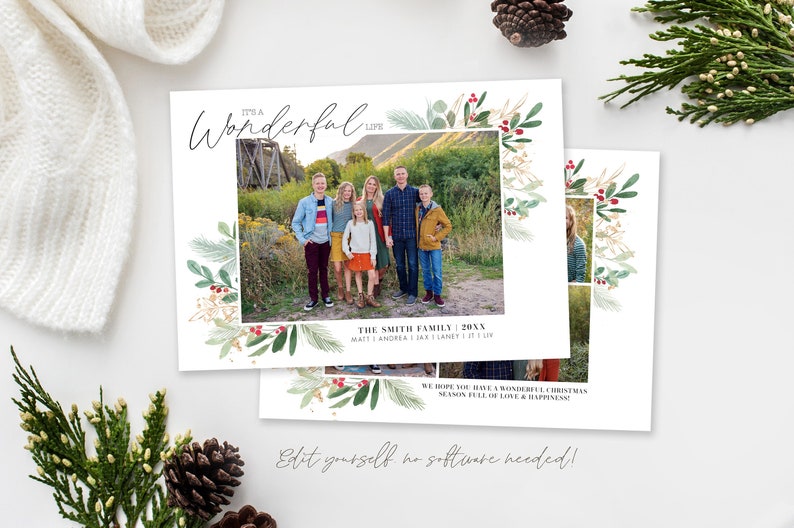 May include: A Christmas card with a watercolor border of green leaves and red berries. The card features a family photo of five people standing in front of a bridge. The text on the card reads "It's a Wonderful" and "The Smith Family 20XX".