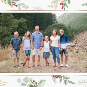 May include: A family of six poses for a photo in a wooded area. The family is standing on a dirt path with trees and a hillside in the background. The family is wearing casual clothing and smiling.