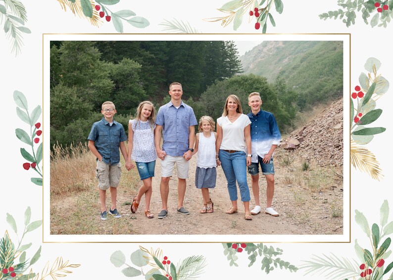 May include: A family of six poses for a photo in a wooded area. The family is standing on a dirt path with trees and a hillside in the background. The family is wearing casual clothing and smiling.