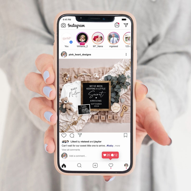 Op de afbeelding: Een zwart ingelijst bord met de tekst "We've been keeping a little secret. Arriving September 2024."  Het bord is omringd door babyartikelen, waaronder een rompertje, een teddybeer en een houten blok met de tekst "Baby".