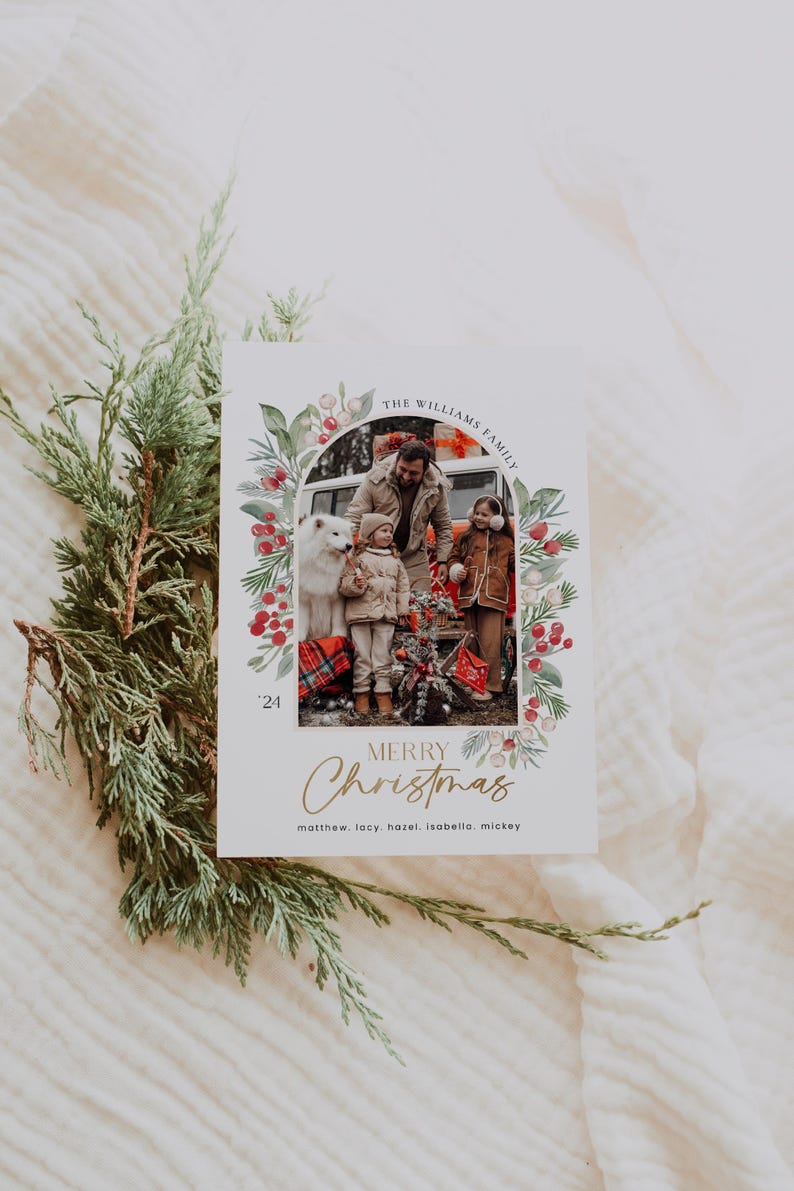 May include: A Christmas card featuring a family of four standing in front of a car. The card has a watercolor border with red berries and green leaves. The text "THE WILLIAMS FAMILY" is at the top of the card, and the text "MERRY Christmas" is at the bottom. The year "24" is also included. The names of the family members are listed below the greeting: "matthew. lacy, hazel, isabella. mickey"