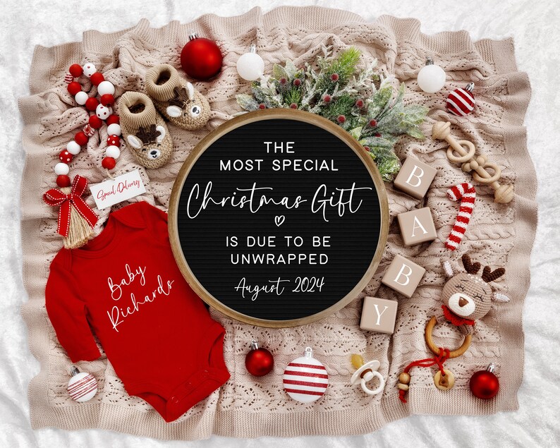 Pu&ograve; includere: Un body rosso per neonato con il testo "Baby Richards" in bianco. Una lavagna con lettere nere con il testo "The Most Special Christmas Gift is Due to Be Unwrapped August 2024". Il body e la lavagna con lettere sono circondati da decorazioni natalizie, tra cui una canna di zucchero, ornamenti e un giocattolo di renna.
