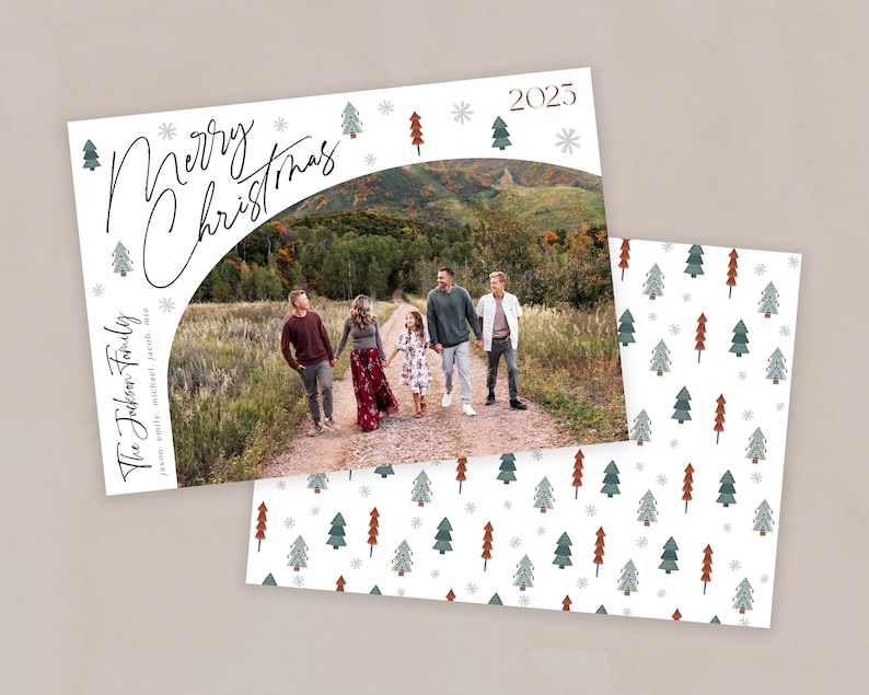 May include: A Christmas card featuring a family of five standing on a dirt road in front of a mountain range. The card has a white background with a green and red Christmas tree pattern and the text "Merry Christmas" and "The Jackson Family" in black cursive.