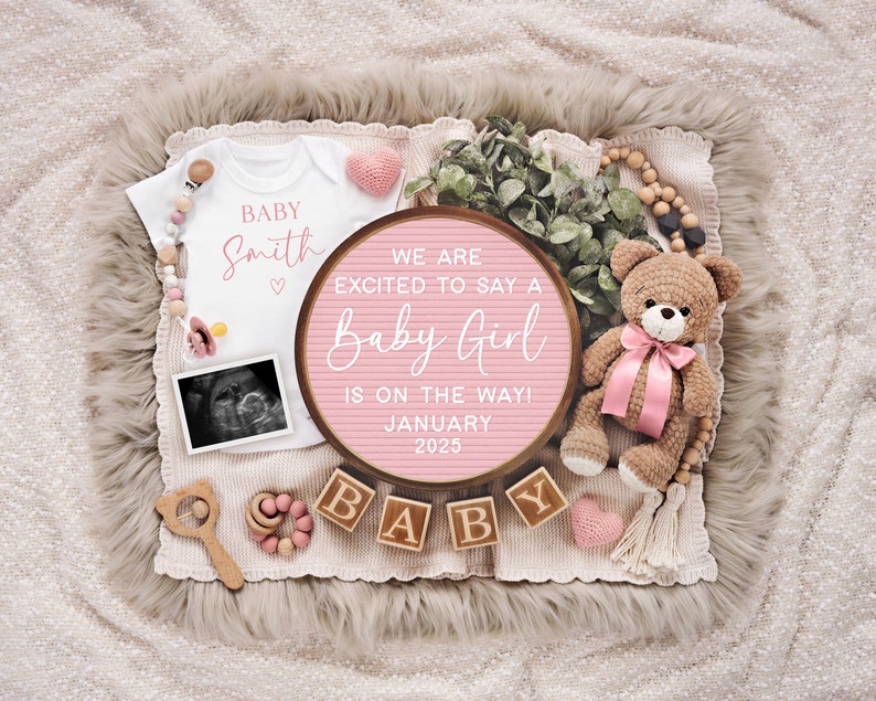 K&ouml;nnte beinhalten: Ein rosa-wei&szlig;es Baby-Ank&uuml;ndigungs-Schild mit dem Text "We are excited to say a Baby Girl is on the way! January 2025". Das Schild ist umgeben von einem wei&szlig;en Strampler mit dem Text "Baby Smith", einem Teddyb&auml;r und Holzkl&ouml;tzen, die "Baby" buchstabieren.