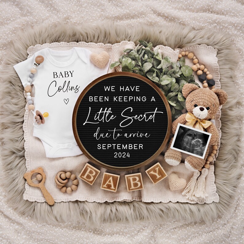 May include: A baby announcement featuring a white onesie with "Baby Collins" printed on it, a letter board stating "We have been keeping a little secret due to arrive September 2024", and a teddy bear holding an ultrasound photo. Wooden blocks spell "BABY".
