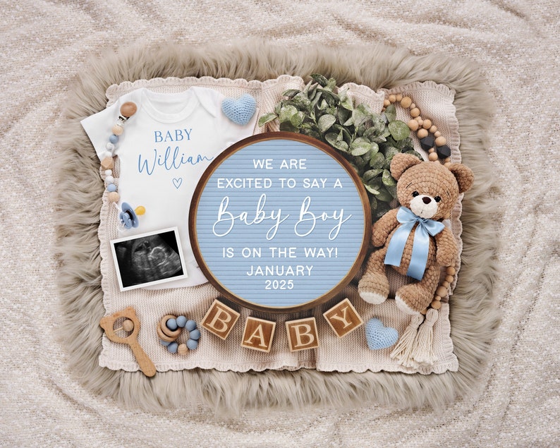 May include: A blue and white letter board with the text "We are excited to say a Baby Boy is on the way! January 2025". The board is surrounded by a white onesie, a teddy bear, and wooden blocks that spell "Baby".