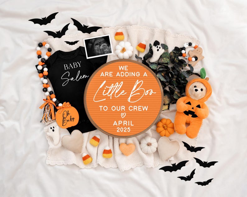 May include: A Halloween-themed pregnancy announcement with a black onesie that says "Baby Salem", a round orange sign that says "We are adding a little Boo to our crew April 2025", and a plush pumpkin-shaped teddy bear.