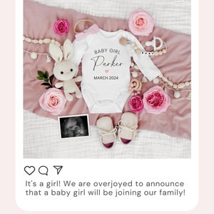 May include: A white onesie with the text "BABY GIRL Parker MARCH 2024" and a pink heart. The onesie is surrounded by pink roses, a crocheted bunny, and a wooden baby rattle.