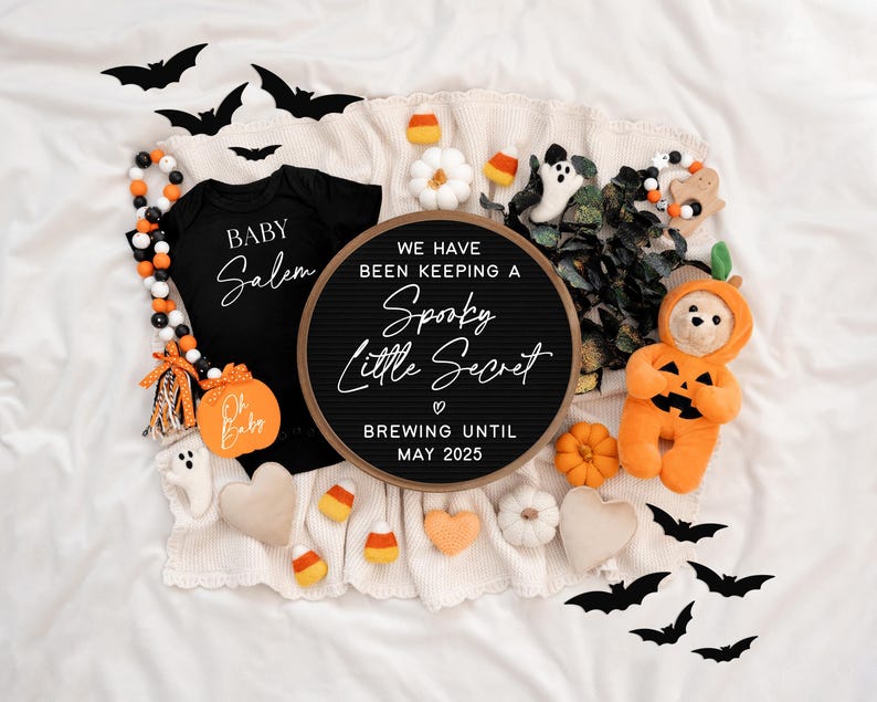 Puede incluir: Un tablero de letras negro con el texto "We have been keeping a Spooky Little Secret ♡ Brewing until May 2025". El tablero est&aacute; rodeado de decoraciones de Halloween, incluyendo un body negro con el texto "Baby Salem", un juguete de peluche con forma de calabaza y un oso de peluche con un disfraz de calabaza.