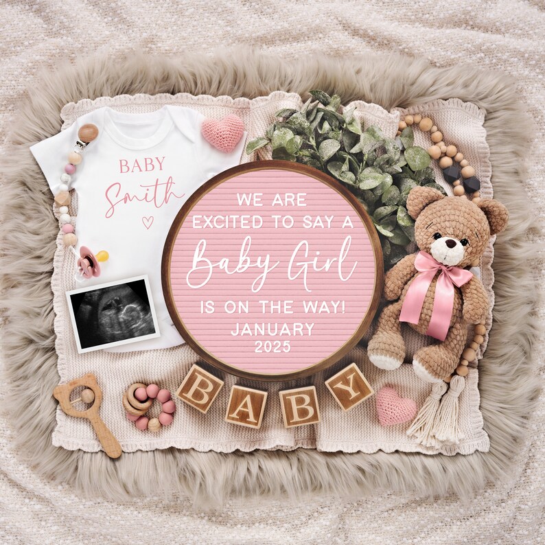 K&ouml;nnte beinhalten: Ein rosa-wei&szlig;es Baby-Ank&uuml;ndigungs-Schild mit dem Text "We are excited to say a Baby Girl is on the way! January 2025". Das Schild ist umgeben von einem wei&szlig;en Strampler, einem Teddyb&auml;r, Holzbl&ouml;cken, die "BABY" buchstabieren, und anderen Baby-Dekorationen.