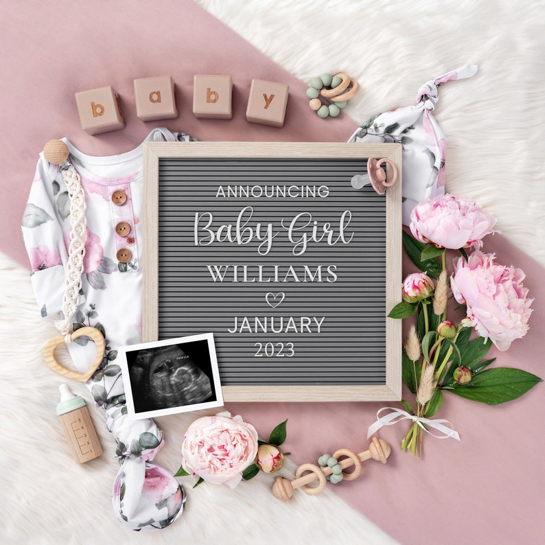 Puede incluir: Un pelele de beb&eacute; rosa y blanco con estampado floral, un tablero de letras que anuncia "Announcing Baby Girl Williams January 2023", un coraz&oacute;n de madera, un biber&oacute;n, un sonajero de madera, un chupete, un coraz&oacute;n de madera, una imagen de ecograf&iacute;a, un ramo de peon&iacute;as rosas y bloques de madera que deletrean "baby" sobre una superficie rosa y blanca.