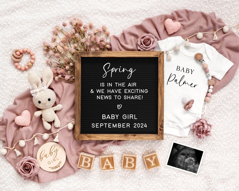 May include: A pink and white baby announcement with a letter board that reads "Spring is in the air & we have exciting news to share! Baby Girl September 2024". There is a white onesie with the text "Baby Palmer" and a pink and white crocheted bunny.