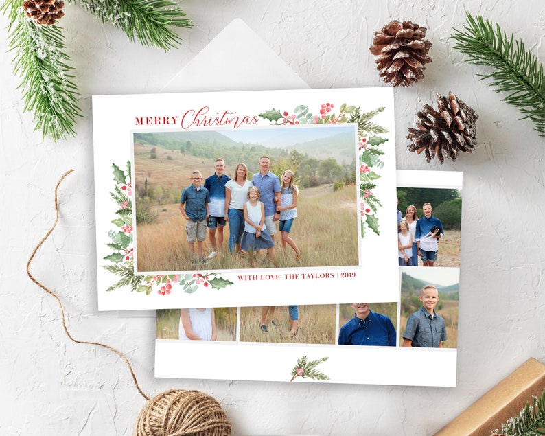 May include: A Christmas card with a watercolor border of holly and berries. The card features a family photo of seven people standing in a field. The text "Merry Christmas" is written in red cursive. The text "With Love, The Taylors 2019" is written in red at the bottom of the card.