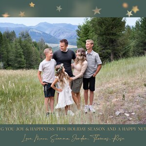 May include: A family of six poses for a holiday photo in a grassy field with mountains in the background. The family is smiling and looking at the camera. The photo is framed with gold stars on a green background. The text "WISHING YOU JOY & HAPPINESS THIS HOLIDAY SEASON AND A HAPPY NEW YEAR! Love, Mare, Sienna, Jordan, Thomas, Rose" is at the bottom of the photo.