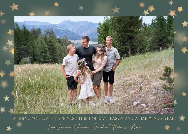 May include: A family of six poses for a holiday photo in a grassy field with mountains in the background. The family is smiling and looking at the camera. The photo is framed with gold stars on a green background. The text "WISHING YOU JOY & HAPPINESS THIS HOLIDAY SEASON AND A HAPPY NEW YEAR! Love, Mare, Sienna, Jordan, Thomas, Rose" is at the bottom of the photo.