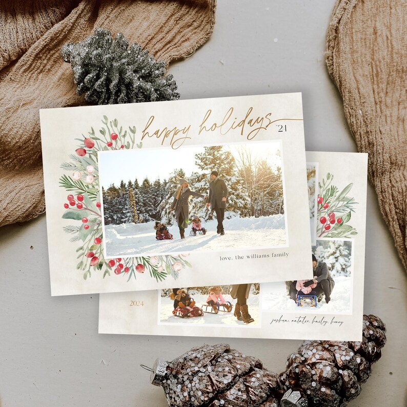 May include: A Christmas card with a watercolor wreath of greenery, berries, and flowers. The card features a photo of a family of four in a snowy landscape. The text "happy holidays" is written in gold script with the year "2021" below. The bottom of the card has the text "love, the williams family" and the year "2024".