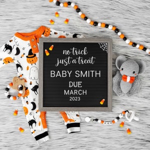 K&ouml;nnte beinhalten: Ein schwarzes Buchstabenbrett mit dem Text "no trick just a treat Baby Smith Due March 2023". Links liegt ein wei&szlig;-oranger Baby-Strampler mit Halloween-Motiv. Rechts befindet sich eine graue geh&auml;kelte Fledermaus mit einer orangefarbenen Schleife.