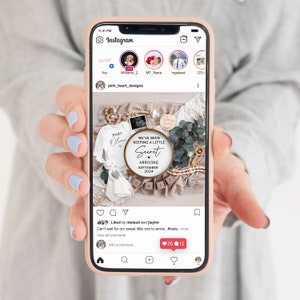 May include: A phone screen displaying an Instagram post announcing a baby's arrival. The post features a wooden sign with the text "We've been keeping a little secret" and "Arriving September 2024". The post also includes a baby onesie with the name "Oliver" on it.