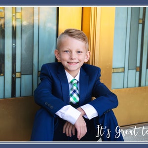 May include: A young boy in a blue suit and a green and white checkered tie sits in front of a gold and blue door. He is smiling and looking at the camera. The text "It's Great to be 8" is written below him.