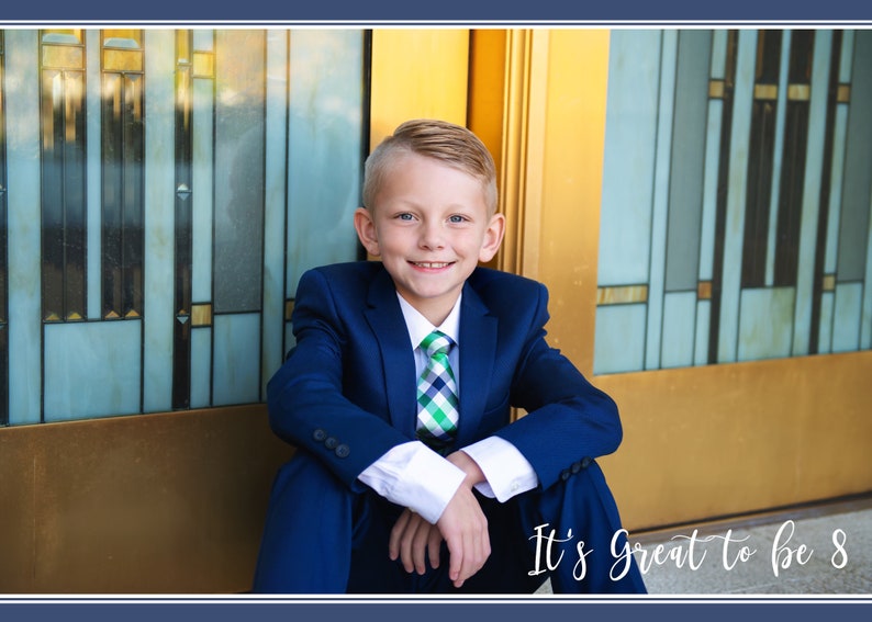 May include: A young boy in a blue suit and a green and white checkered tie sits in front of a gold and blue door. He is smiling and looking at the camera. The text "It's Great to be 8" is written below him.