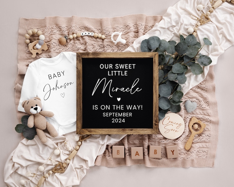 May include: A baby announcement with a white onesie that says "Baby Johnson" and a chalkboard sign that says "Our Sweet Little Miracle is on the way! September 2024". There are also wooden blocks that spell out "BABY" and a wooden sign that says "Coming Soon".