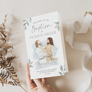 May include: A white card with green foliage and a watercolour illustration of a baptism. The text reads "Welcome to the Baptism of Jackson Miller. The Church of Jesus Christ of Latter-day Saints. Date Here."