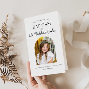 Peut inclure: Une carte d'invitation de baptême blanche avec le texte "Bienvenue au baptême de Lila Madeline Carter". La carte présente une photo d'une jeune fille portant une couronne de fleurs. L'Église de Jésus-Christ des Saints des Derniers Jours est également mentionnée.