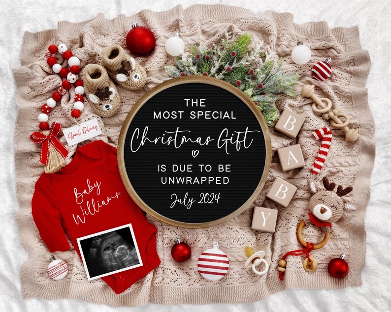 Pu&ograve; includere: Un body rosso con il testo "Baby Williams" e un'immagine di ecografia. Una lavagna con lettere nere con il testo "The Most Special Christmas Gift is Due to Be Unwrapped July 2024". Il body, la lavagna con lettere e altre decorazioni natalizie sono disposte su una coperta di maglia beige.
