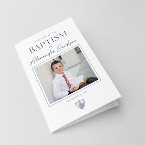 May include: A white card with the text "Welcome to the Baptism of Alexander Jackson" and a photo of a young boy in a white shirt and tie holding a book. The date "September 8, 2021" is printed below the photo.