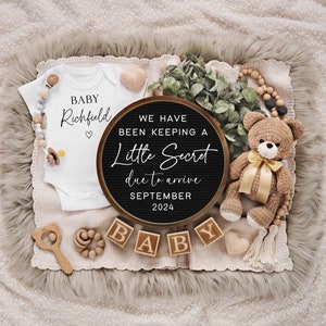 May include: A baby announcement featuring a white onesie with "BABY Richfield" printed on it, a black circular sign with text, wooden blocks spelling "BABY", and a crocheted teddy bear with a gold ribbon. The announcement is set on a neutral-toned blanket.