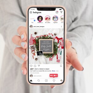 May include: A Christmas-themed baby announcement on a phone screen. A chalkboard sign reads "We are expecting! Baby Smith September 2023". The sign is surrounded by a green wreath with red berries, a red and white striped baby outfit, a reindeer rattle, and a small framed ultrasound image.