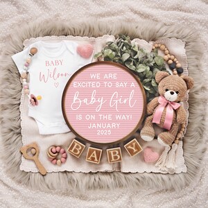 K&ouml;nnte beinhalten: Rosa-wei&szlig;e Baby-Ank&uuml;ndigung mit einem Holzschild, auf dem steht "We are excited to say a Baby Girl is on the way! January 2025". Es gibt einen wei&szlig;en Strampler mit dem Text "Baby Wilson" und einen Teddyb&auml;r mit einer rosa Schleife.