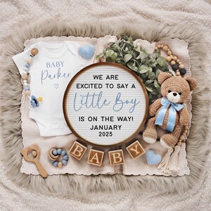 以下が含まれることがあります： 「We are excited to say a little boy is on the way! January 2025」と書かれた木製のレターボード。ボードの周りは、「Baby Parker」と書かれた白いロンパース、青いリボンをつけたテディベア、そして「Baby」と綴られた木製のブロックで囲まれています。